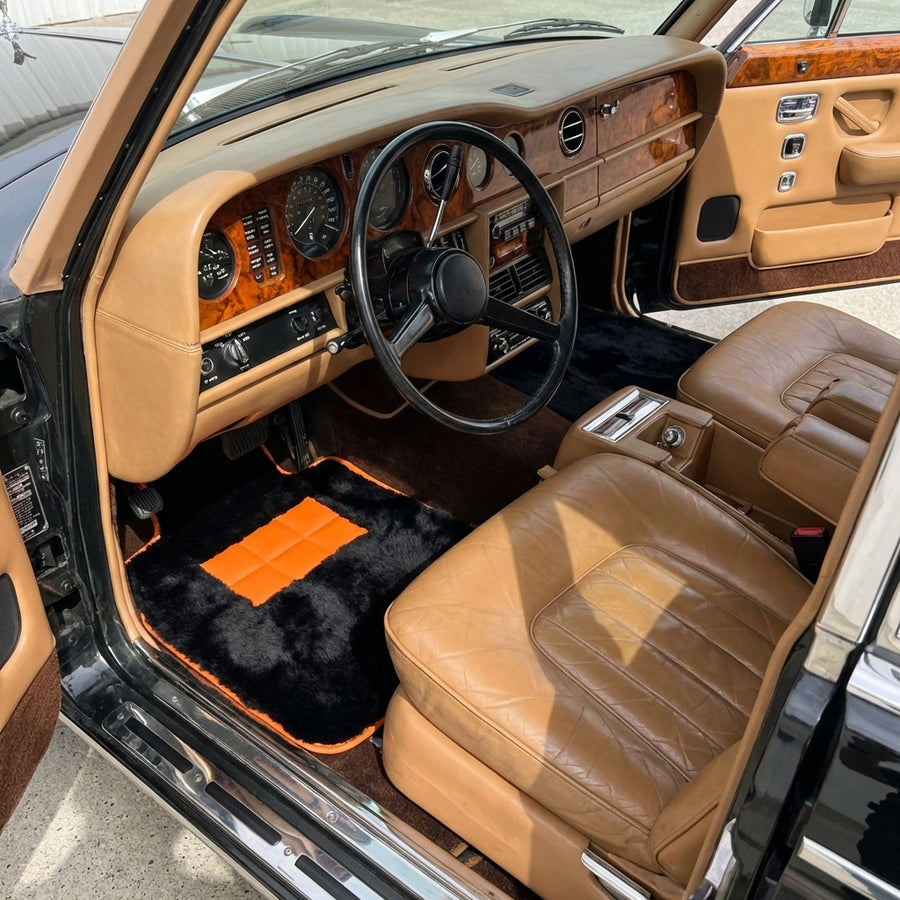 Svarte saueskinnsmatter for Rolls-Royce Wraith (2013–2023) med oransje lærdetaljer